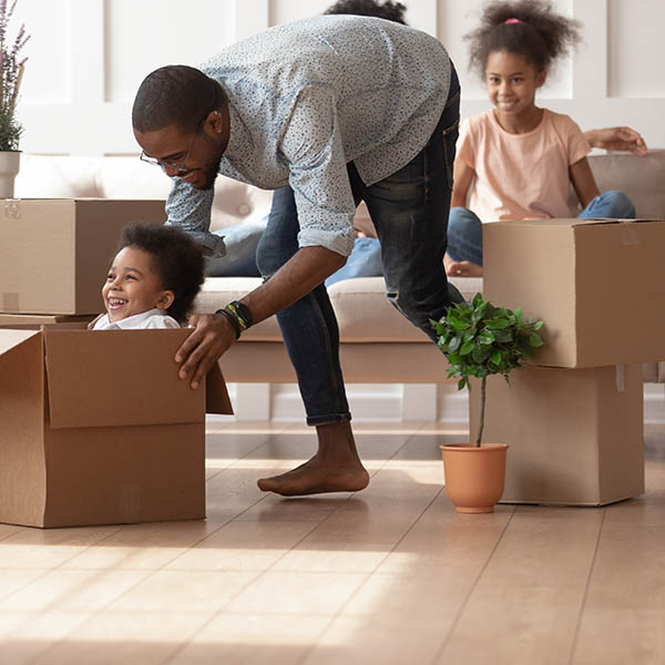 Father playing with son ride sitting in cardboard box