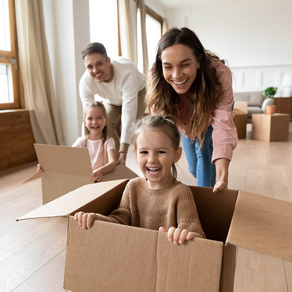 Happy parents playing with little kids riding in box