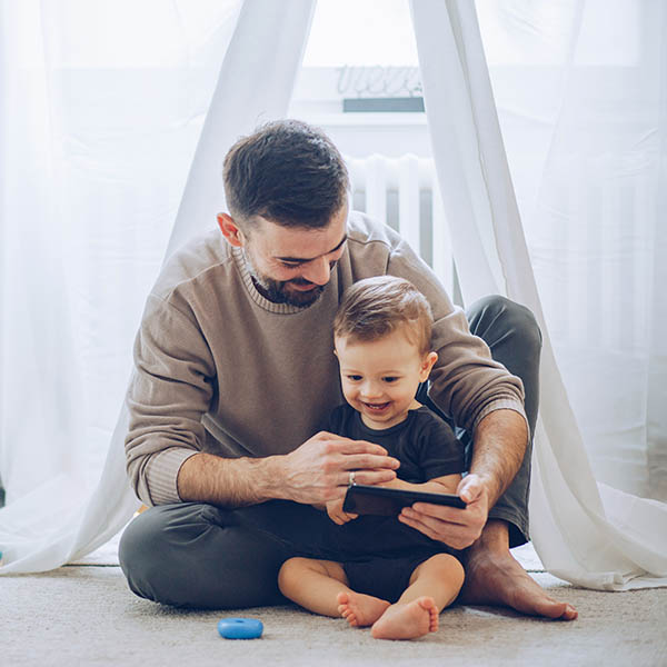 Father & son sitting on floor & watching mobile
