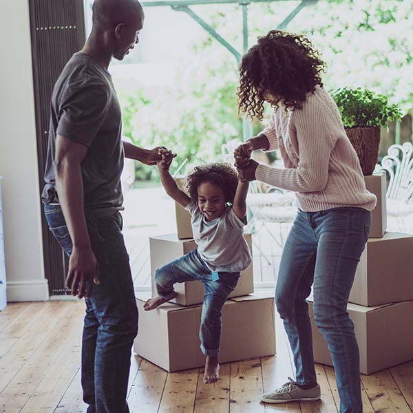 Playful parents holding son's hands in new house